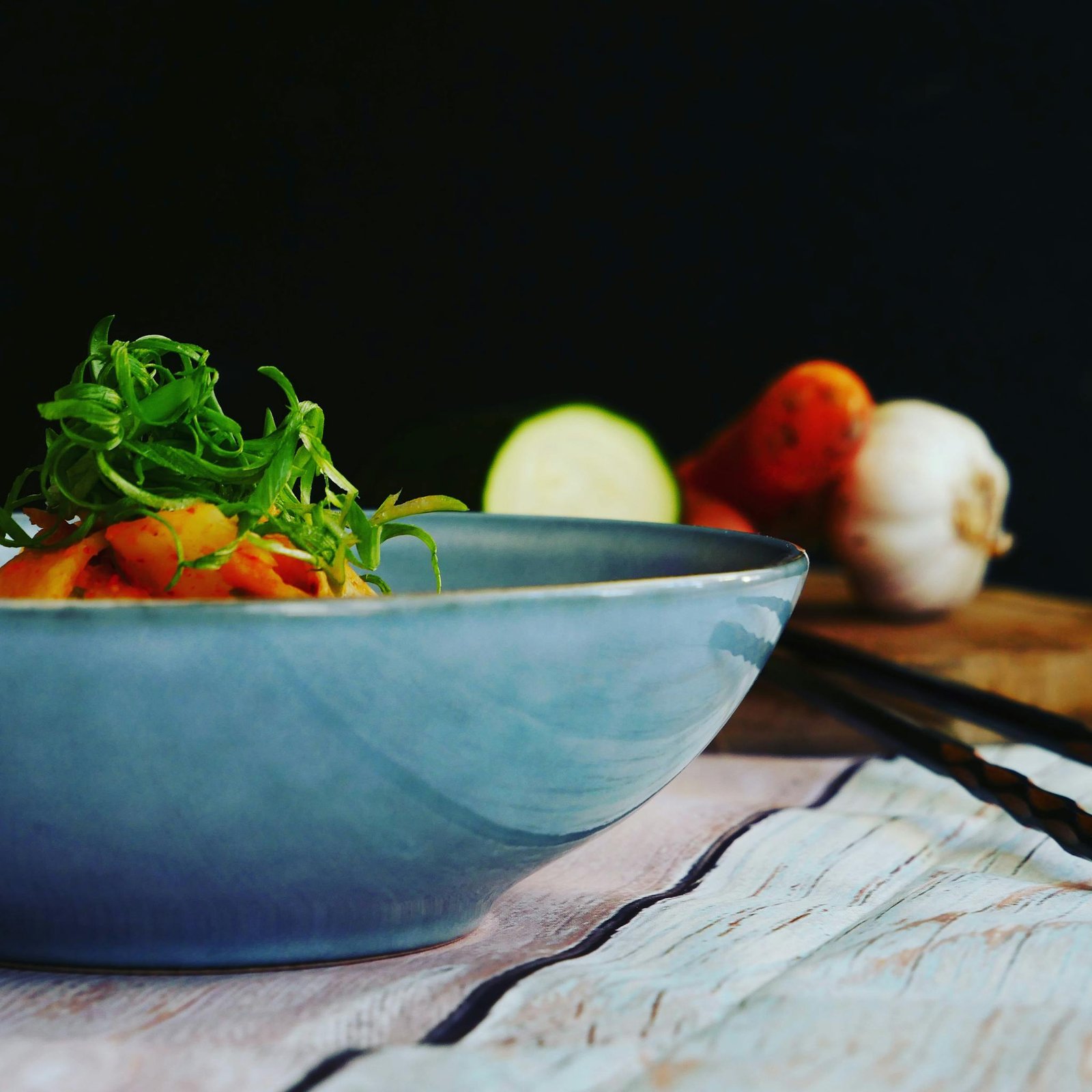 Appetizing vegetable dish garnished with greens in a stylish blue ceramic bowl, perfect for healthy diet visuals.